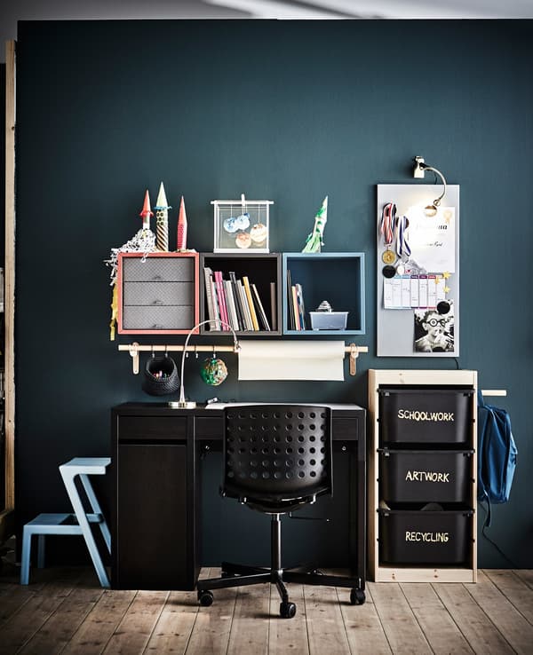 A child’s workspace with lots of EKET open storage square cabinet units mounted to a dark wall.