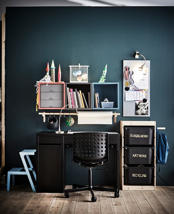 A child’s workspace with lots of storage in front of a dark wall.