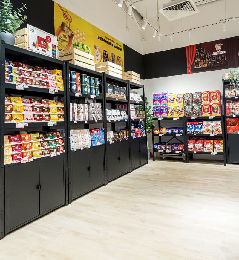 A chocolate store featuring several black cabinets of assorted chocolates on display on a light birch floor.