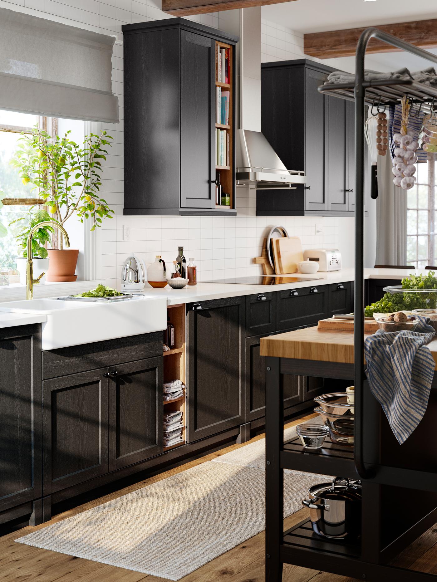 A classic style kitchen with stained black cabinet fronts, a white worktop and a white sink with visible front.