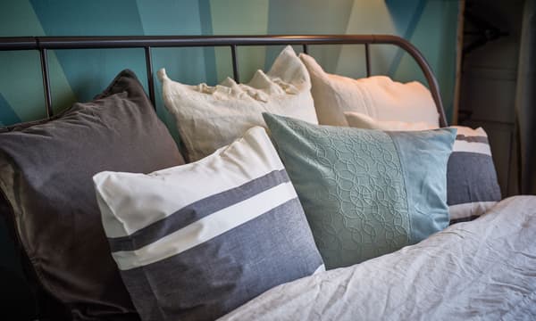 A close-up image of a bed made with grey-toned linens.