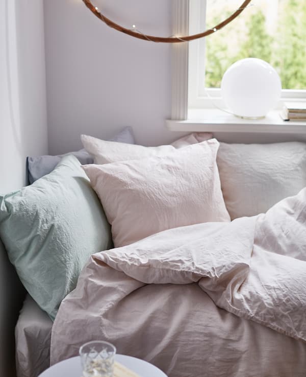 A close-up image of a cozy bed with hand-dyed pastel bed linens.