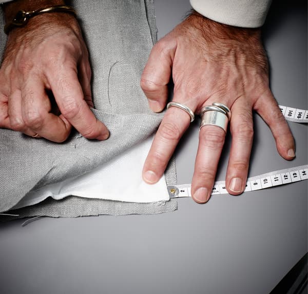 A close up image of a hands, that is layering up grey fabric and wadding to start sewing a soundproof curtain.