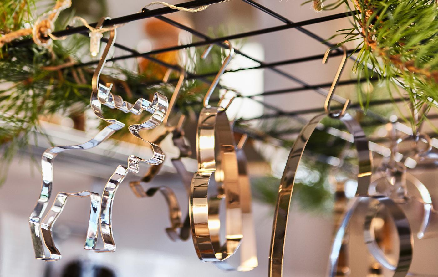 A close-up image of a wire trellis hung above a kitchen island, decorated with greenery and cookie cutters.