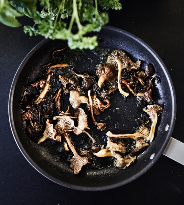 A close-up image of mushrooms frying in a pan.