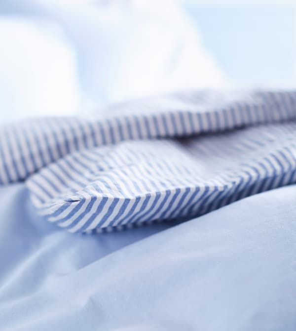 A close-up image of white and blue striped bed linens.
