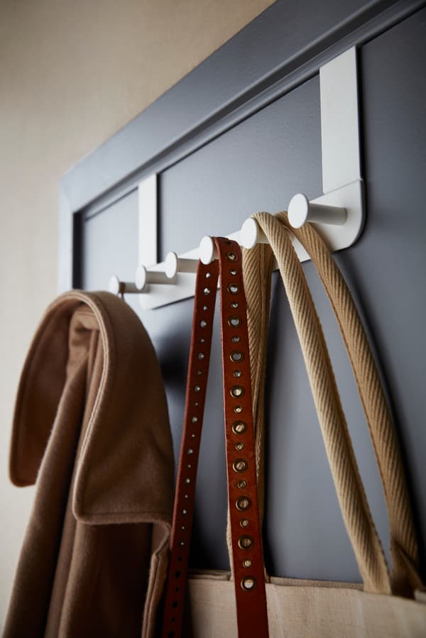 A close up image of white hooks with clothing and accessories hanging from them.