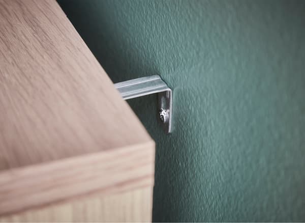 A close-up of a chest of drawers fastened to a bedroom wall.