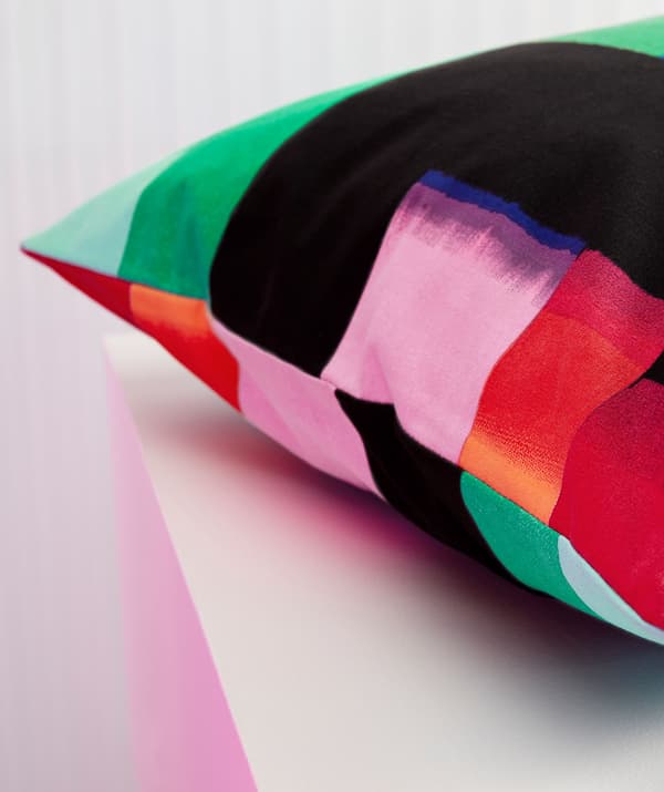 A close-up of a cushion with a multicolour pattern.