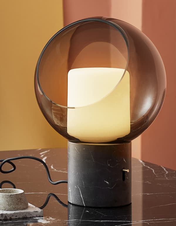 A close-up of a glass globe table lamp with marble base.