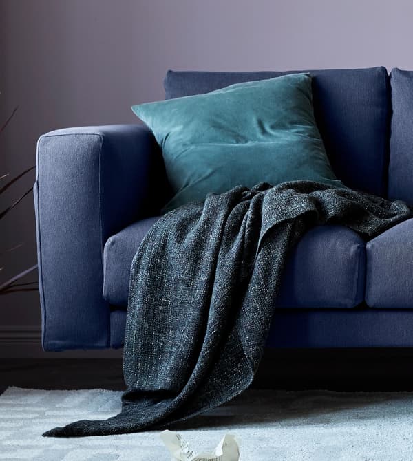A close up of a grey sofa with a throw and cushion.