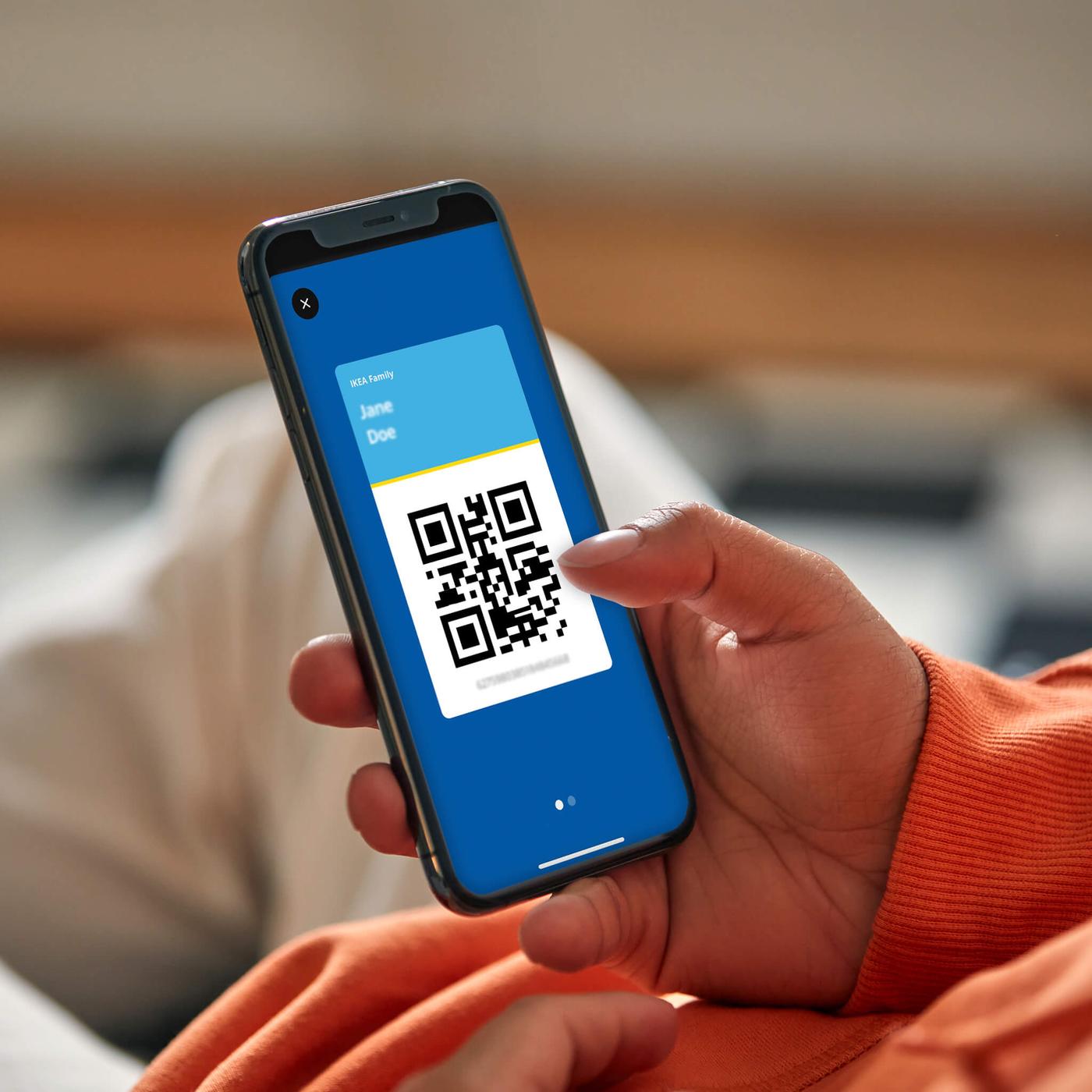 A close-up of a hand holding a mobile phone with a QR code.