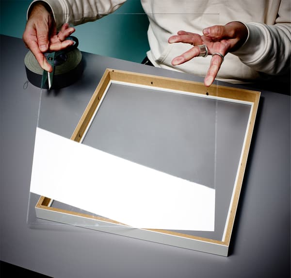 A close up of a person’s hands, removing plastic from a photo frame.