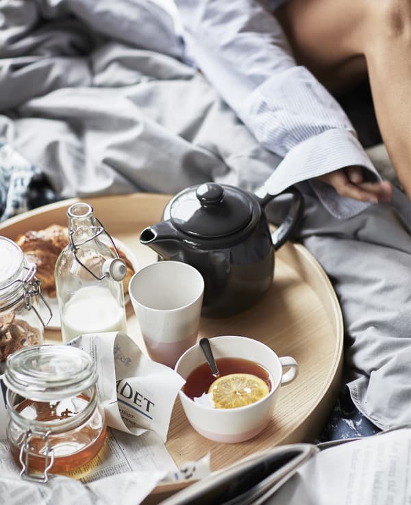 A close-up of a round tray holding a teapot, mugs and jars.