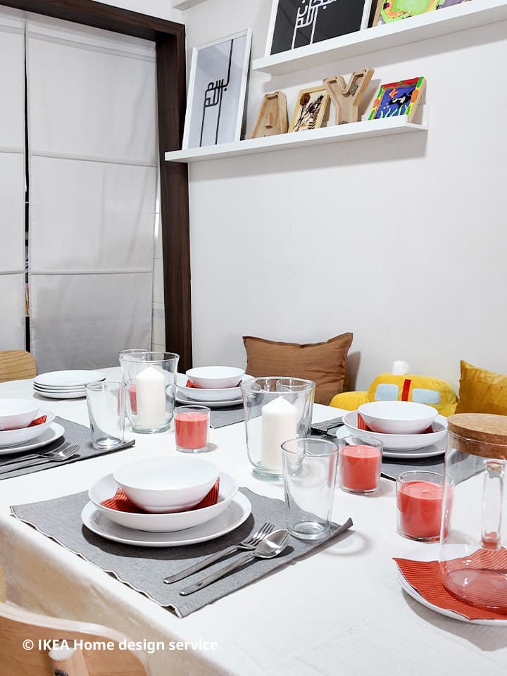 A close-up of a table setting with place mats, napkins, plates, bowls, and candles in a refreshed 3-room HDB flat in Singapore, designed by IKEA home design service