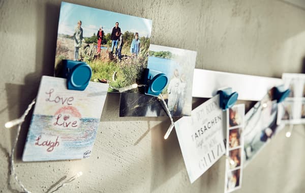 A close-up of photographs and pictures clipped on a rail.
