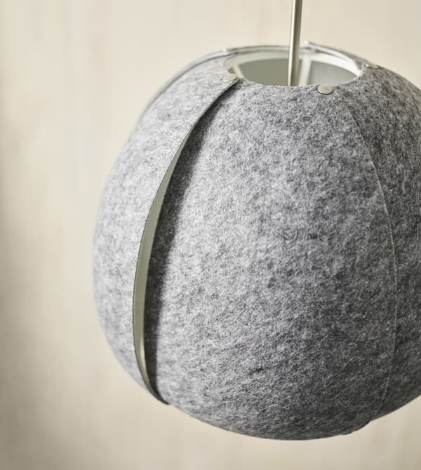 A closeup of a dark grey felt IKEA VINTERGATA pendant lamp, partially made from recycled PET-plastic.
