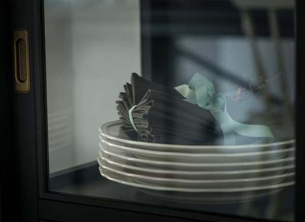 A closeup of white plates and fabric napkins sitting inside a glass-door cabinet.