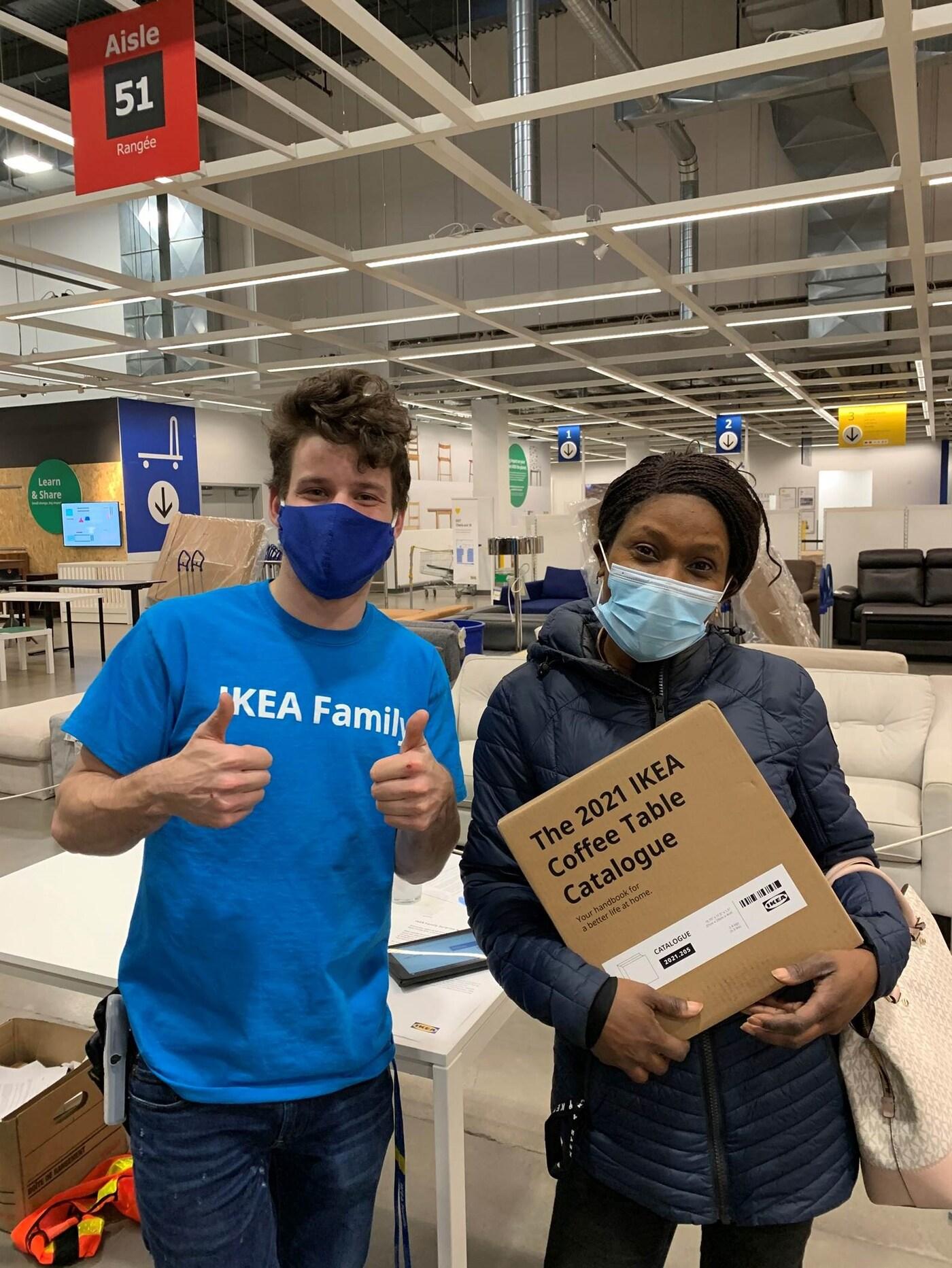 A co-worker giving the "thumbs up" to an IKEA Family member holding her IKEA Coffee Table Catalogue 