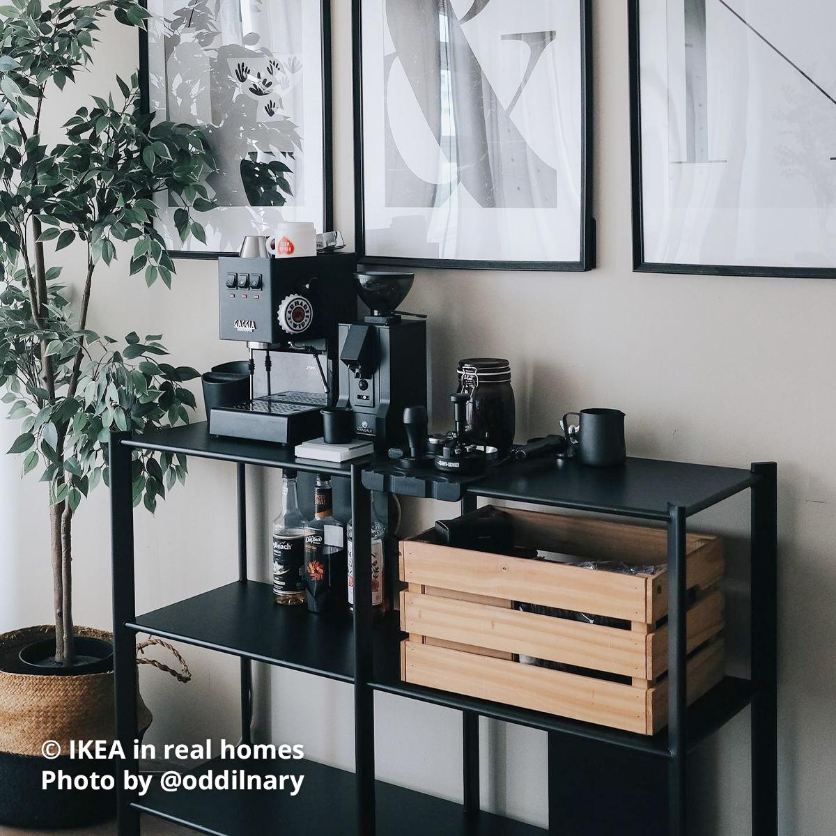 A coffee area within the living room area - A black JÄTTESTA shelving unit with coffee machine, coffee grinder and other equipments placed on the first tier of the shelving, while a KNAGGLIG wooden crate box is placed on the second tier with other coffee area essentials. Photo by instagrammer @nbhha for IKEA in real homes ©