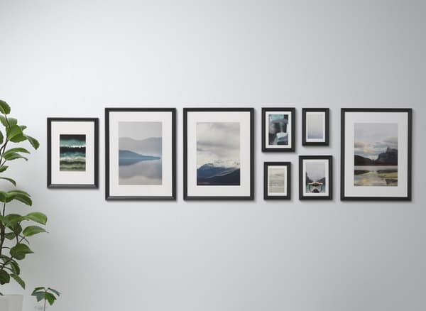 A collection of artwork in black frames on a white wall.