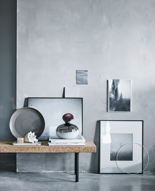 A collection of black and white pictures arranged by a grey wall