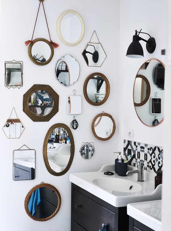 A collection of different mirrors on a bathroom wall.