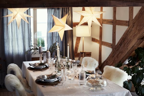 A cosy, rustic Christmas table setting with with a black tablecloth, black plates, wooden boards, and branches from the forest.