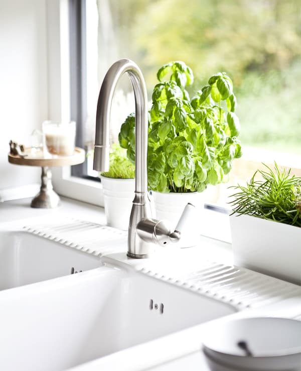 A country-style white kitchen sink infront of a window.