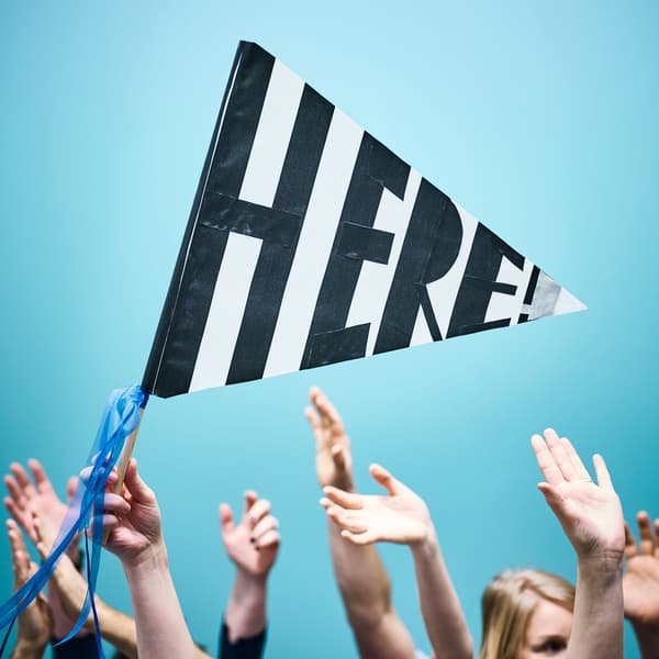 A crowd of people have their hands in the air, while one person waves a handmade flag that says 