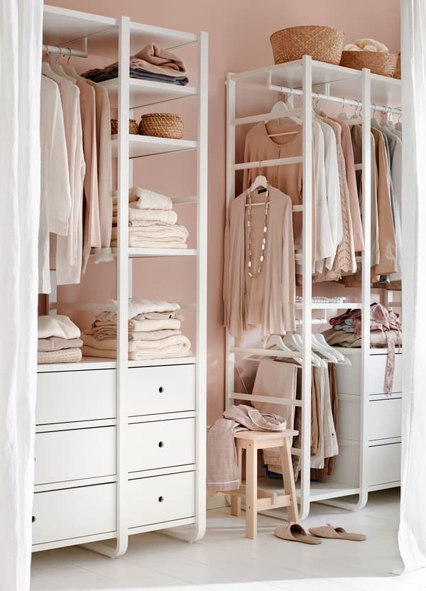 A curtained nook containing an IKEA ELVARLI open storage system filled with clothing.