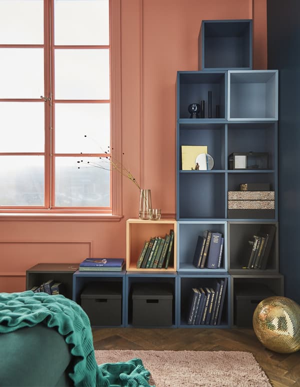 A custom modular cabinet made of EKET squares to make a reverse L-shape against a corner. One is orange to bring a pop.