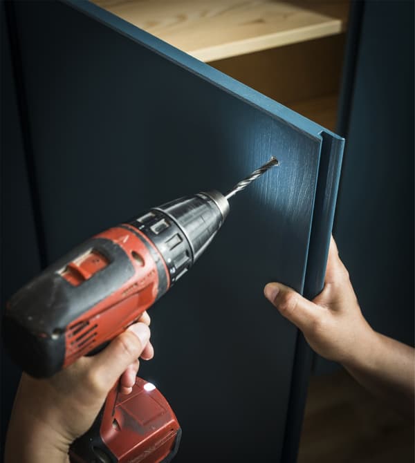 A custom painted IVAR cabinet is being drilled to add a door handle.