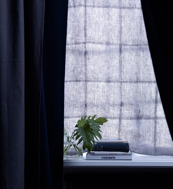 A dark blue padded curtain and dark blue blind combination at this bedroom window blocks out light and sound.