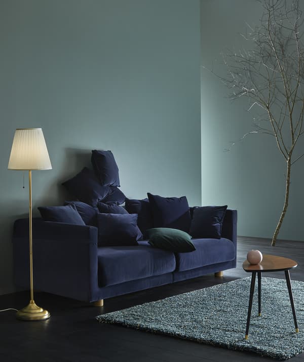 A dark blue velvet sofa in a living room.