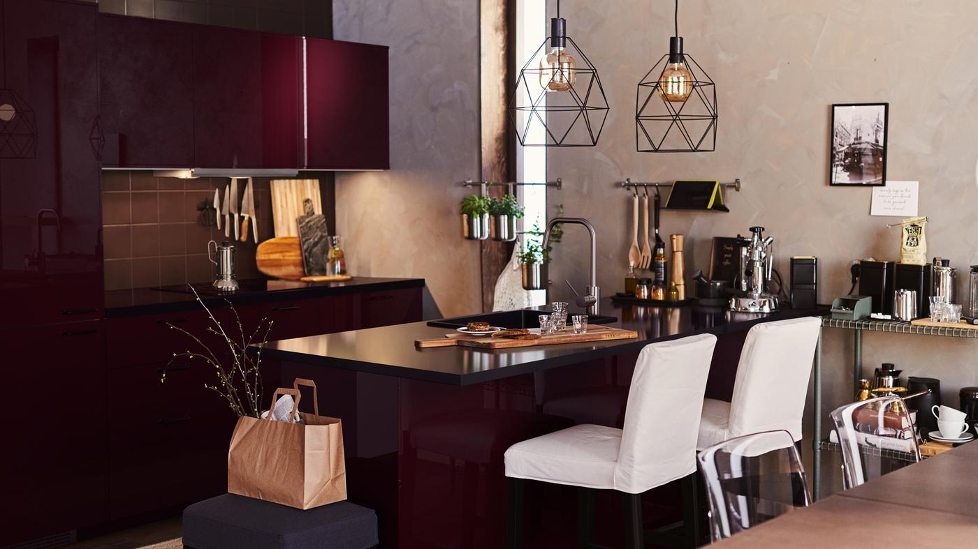 A dark brown kitchen with METOD cabinet and an island. White bar stools at the island, and two BRUNSTA lamps hang overhead.