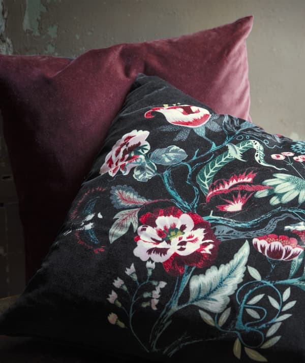 A dark floral and red velvet cushion.