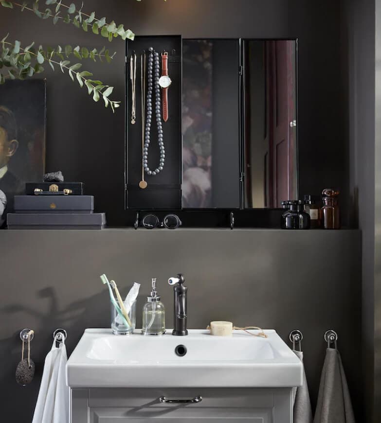 A dark grey bathroom with a white sink and hand cloths hanged on each side of the sink.