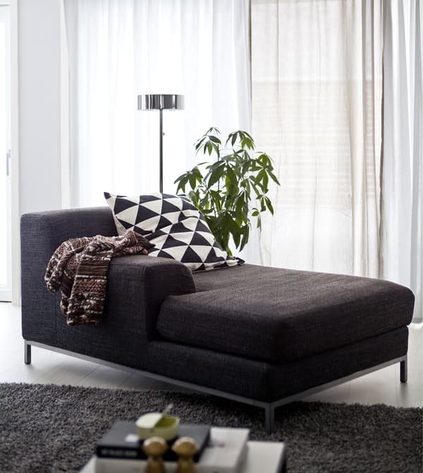 A dark grey chaise longue in a monochrome living space.