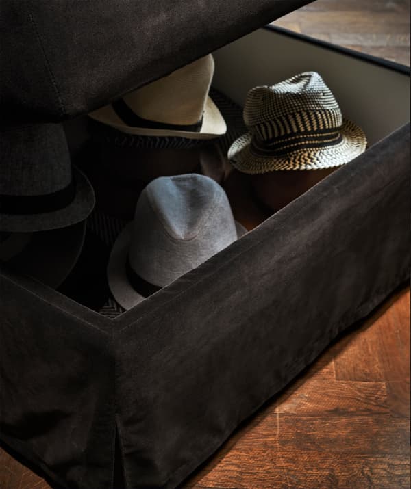 A dark grey FÄRLÖV footstool with storage with hats inside.