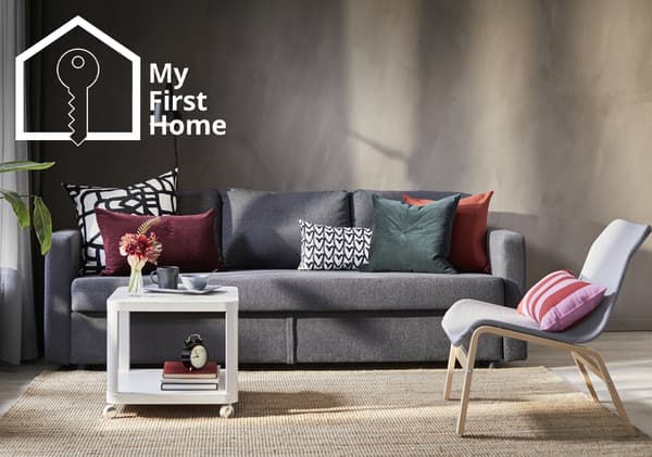 A dark grey FRIHETEN 3-seat sofa is placed on top of natural flatwoven rug in the living room, in front of a white TINGBY side table on castors. The top left corner shows the 