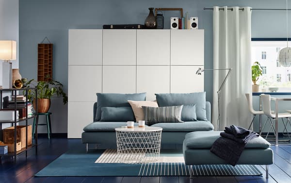A dark walled living room furnished with IKEA SÖDERHAMN turquoise three-seater sofa and footstool.