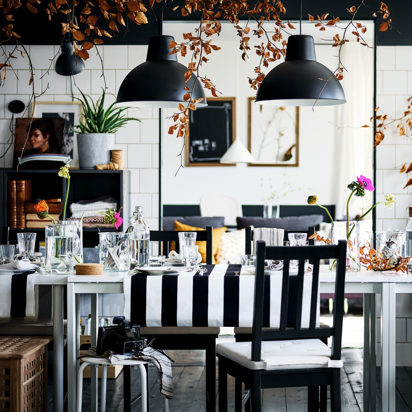 A decked-out black-and-white dining area with brown-black STEFAN chairs and MARIUS stools round two white MELLTORP tables.