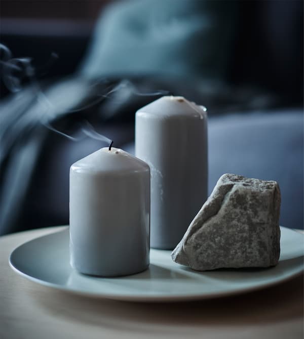 A decoration with two block candles and a rock.