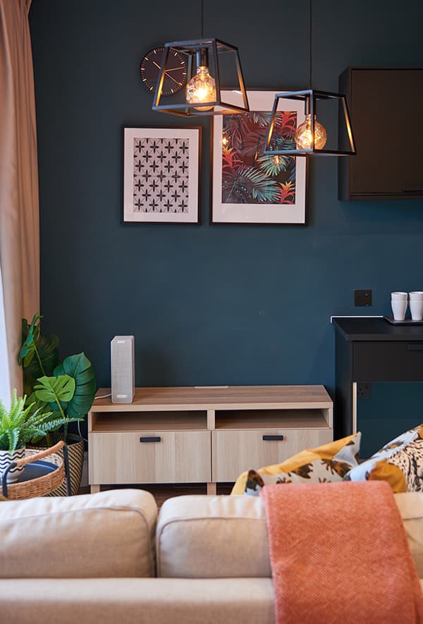 A decorative ceiling light shining over a white sofa in a dark blue room.