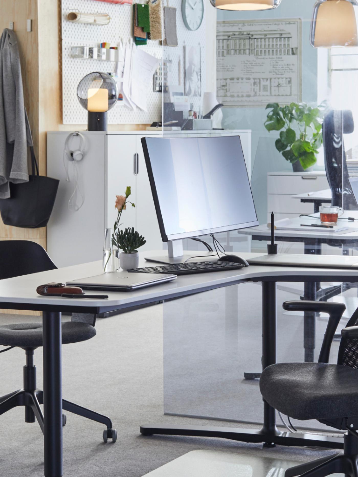 A desk in an office with a computer and a chair on the foreground