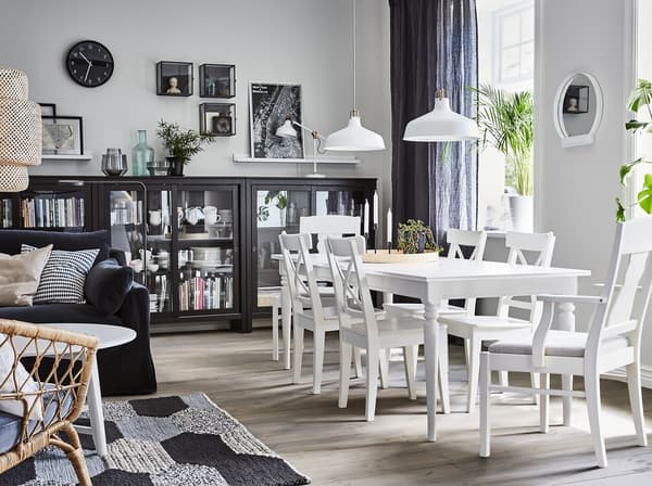 A dining area with white INGATORP extendable dining table and HEMNES black glass door cabinets to store dinnerware.