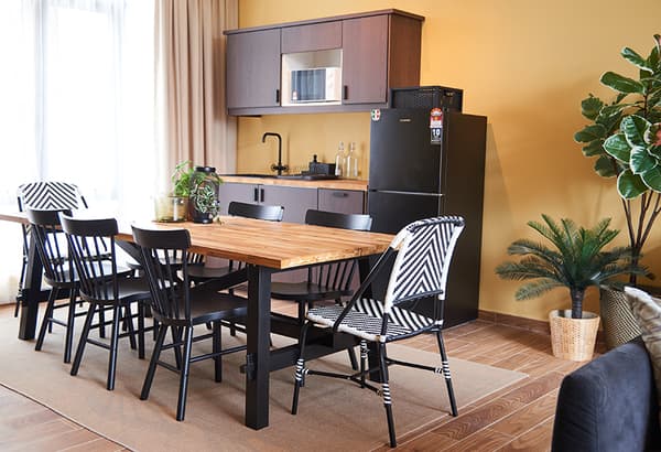 A dining room setting featuring a kitchenette, dining table and chairs.