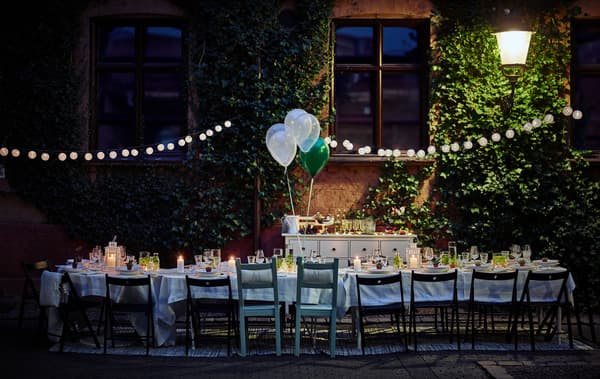 A dining table for a wedding is set up in a courtyard at night time.