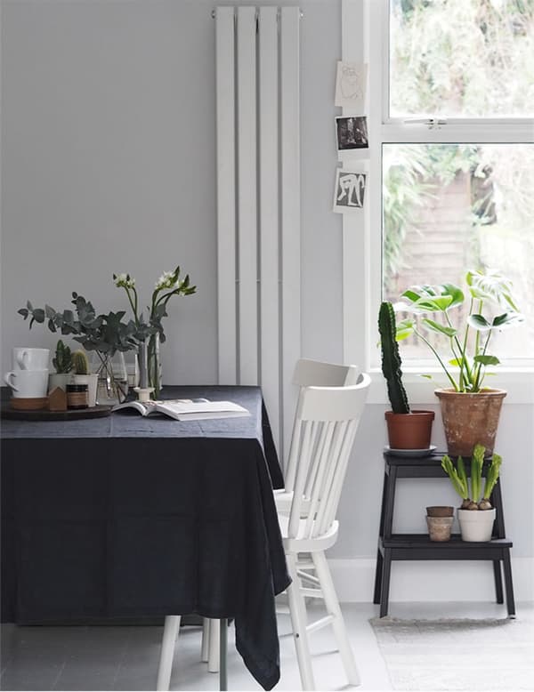 A dining table with dark tablecloth and white dining chairs.